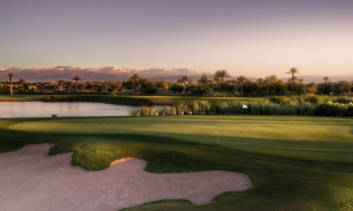 Marrakech golf course at sunset, with a bunker in the foreground and the Atlas on the horizon
