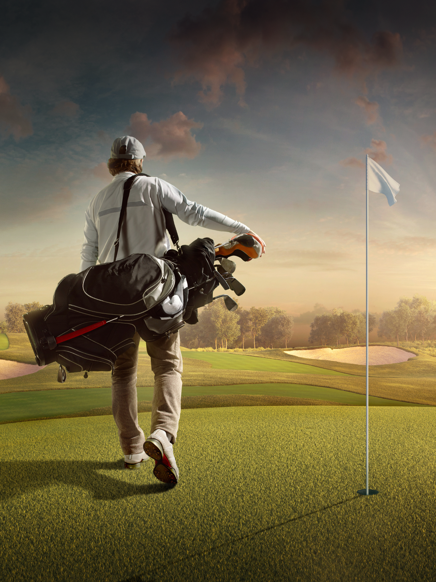 Golfer carrying his bag on his shoulder near a green