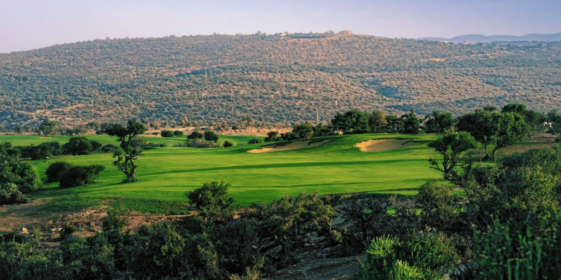 Tazegzout Golf at Taghazout Bay: fairways among argan trees, hills behind