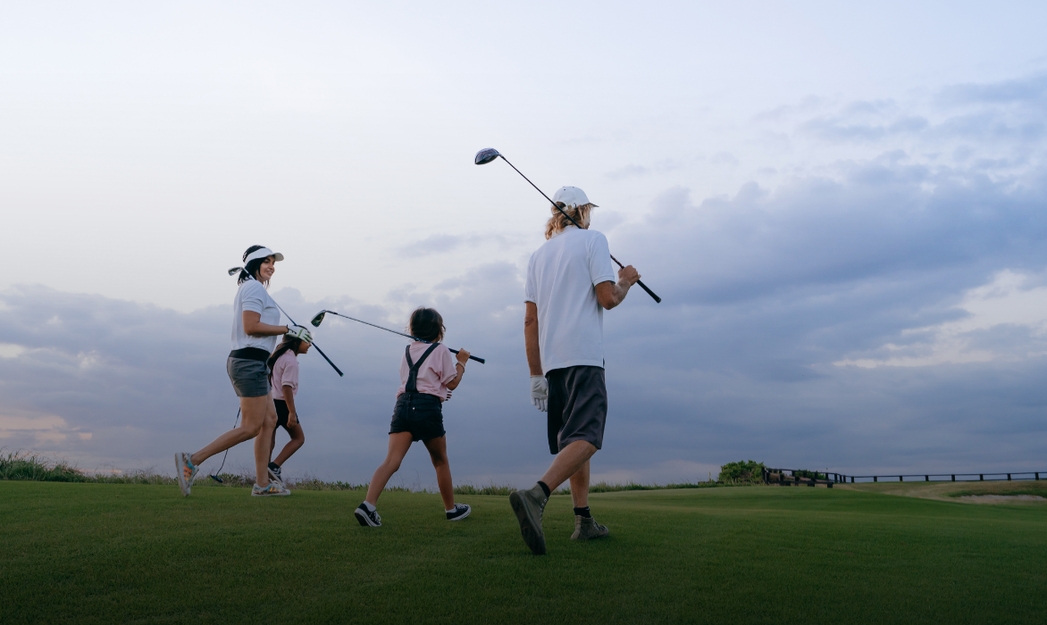 A family walking on a course, clubs in hand