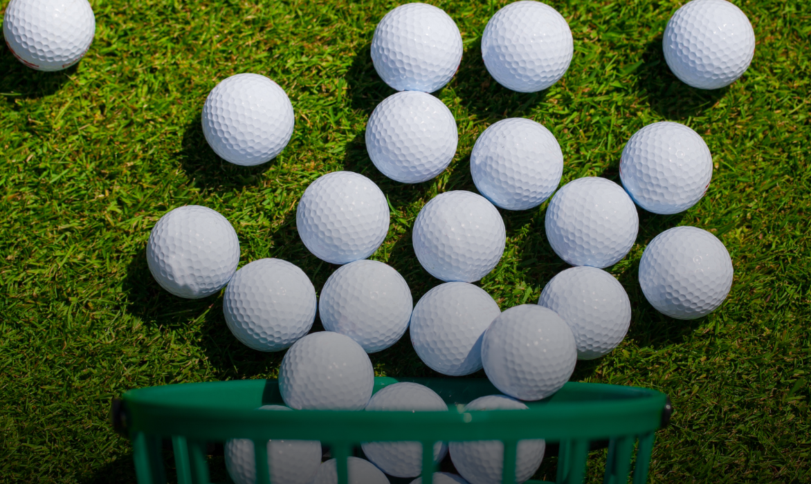 Practice balls on the grass beside a green range basket