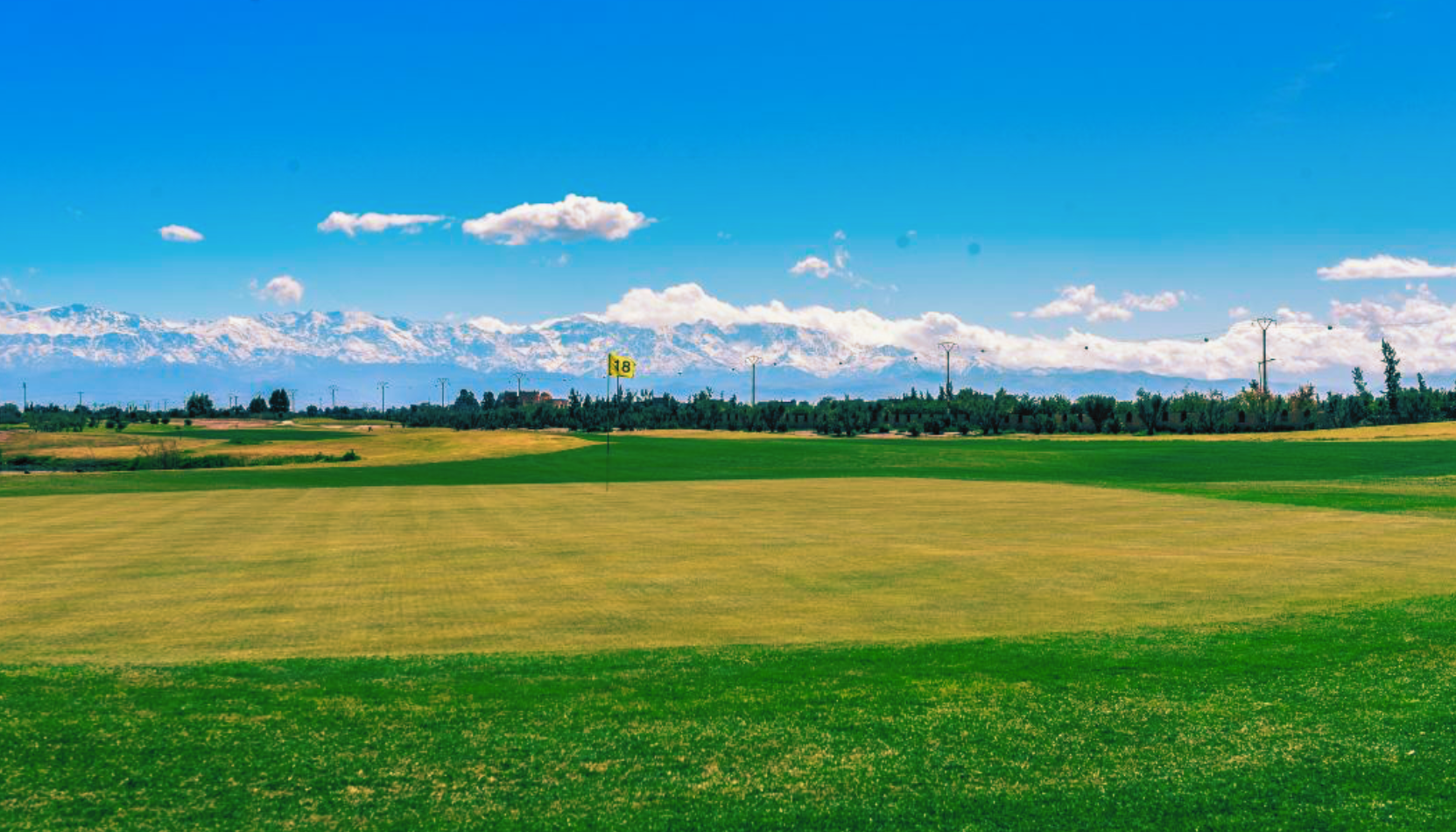 Fairway du Tony Jacklin (Argan Golf Resort) à Marrakech, ciel dégagé et Atlas enneigé au loin