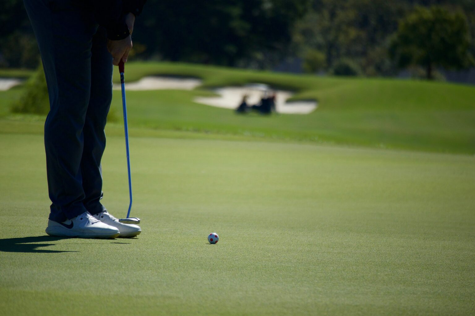 Golfeur en train de putter sur un green, drapeau à quelques mètres