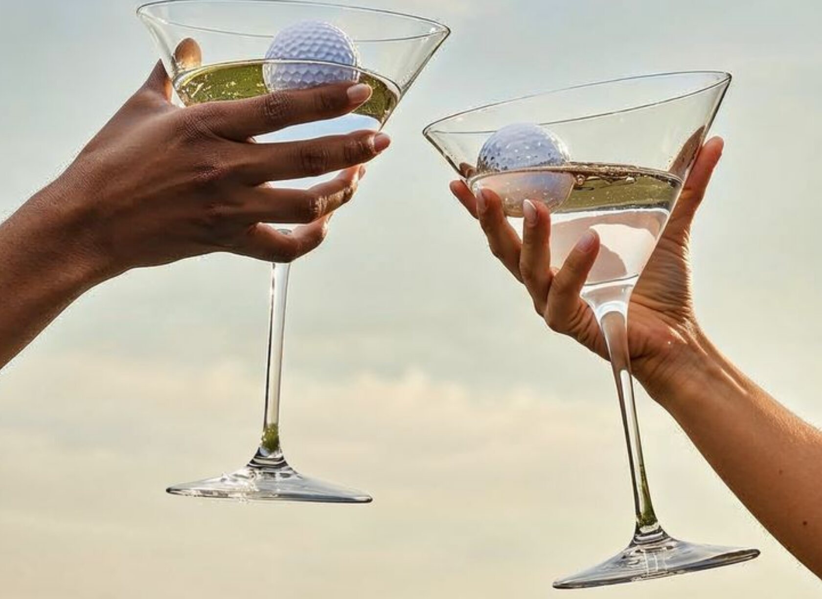 Two glasses raised in a toast, a golf ball in each